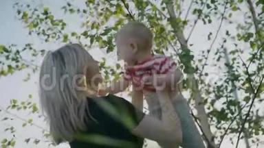 迷人的母亲抱着小儿子在怀里，俄罗斯桦树作为背景慢动作4k